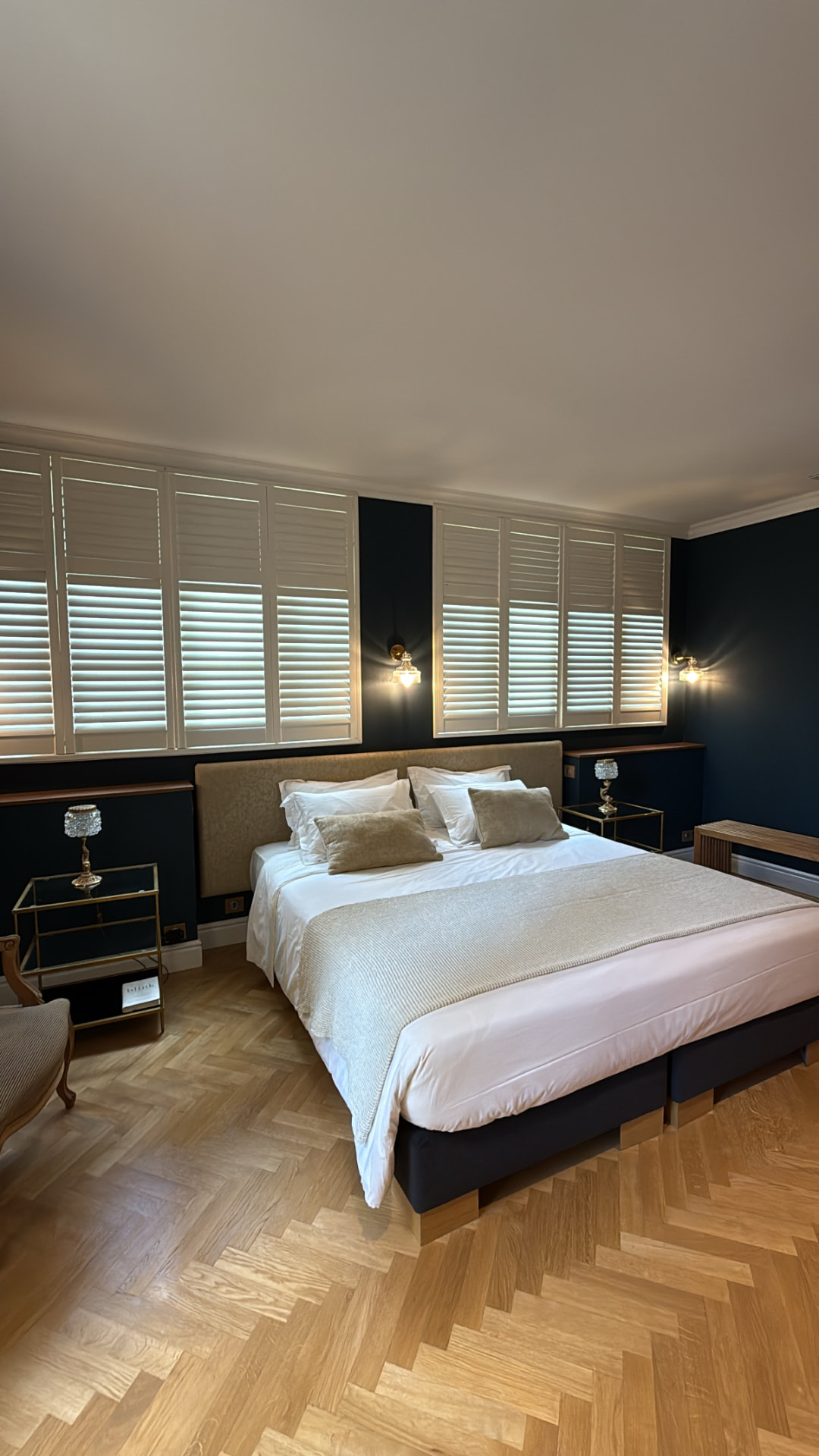 Chambre d’un appartement aixois : murs bleu profond, volets blancs et parquet en chevrons